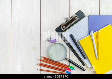 Stylos, carnets, crayons, taille-crayons sur fond blanc. Vue de dessus, espace de copie. Retour à l'école. Banque D'Images