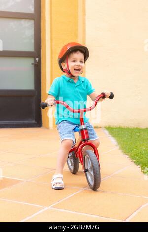 les enfants d'âge préscolaire apprennent à monter à vélo avec un visage souriant pour l'obtenir et profiter de la liberté avec un casque de protection sur sa tête pour la sécurité routière o Banque D'Images
