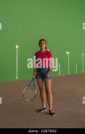 Adolescente en T-shirt rouge et short en denim avec une raquette de tennis et un concept de sport de pratique et de jeu de balle Banque D'Images