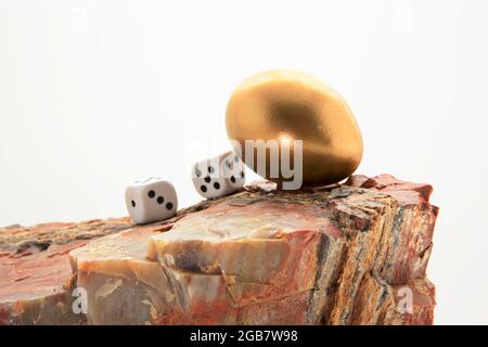 Les dés de jeu avec l'oeuf de nid d'or sur le rocher se combinent en avertissement symbolique pour éviter le risque financier pour un oeuf de nid d'investissement Banque D'Images