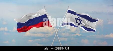 Drapeaux de la Russie et d'Israël agitant dans le vent sur les mâts de drapeaux contre le ciel avec des nuages le jour ensoleillé. Symbolisant la relation, le dialogue entre deux pays Banque D'Images