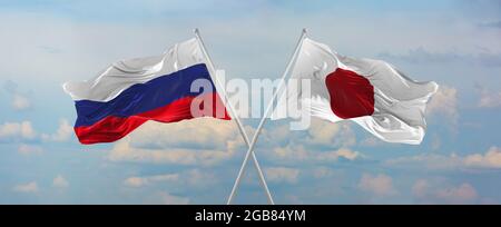 Drapeaux de la Russie et du japon agitant dans le vent sur les mâts de drapeaux contre le ciel avec des nuages le jour ensoleillé. Symbolisant la relation, le dialogue entre deux pays Banque D'Images