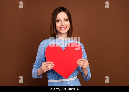 Photo de joli bob Hairdo jeune dame tenir coeur porter blouse bleue isolée sur fond brun de couleur Banque D'Images
