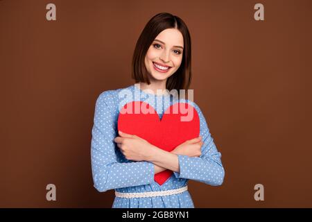 Photo de flirty bob hairdo jeune femme câlin coeur porter blouse bleue isolée sur fond brun couleur Banque D'Images