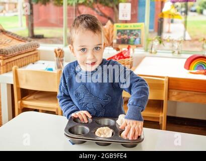 jeune enfant prétendant faire cuire des cupcakes Banque D'Images