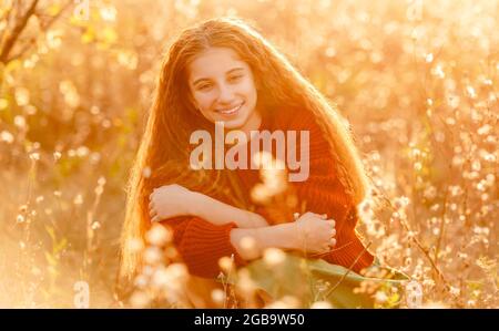 Fleurs d'automne dans les mains de jeunes filles sur la nature colorée et ensoleillée Banque D'Images