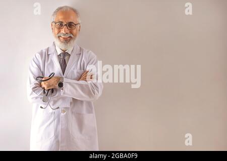 PORTRAIT D'UN MÉDECIN SENIOR HEUREUX DEBOUT DEVANT L'APPAREIL PHOTO Banque D'Images