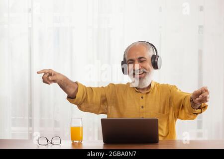 UN VIEIL HOMME HEUREUX DE PROFITER DE LA MUSIQUE TOUT EN ÉTANT ASSIS À LA MAISON Banque D'Images