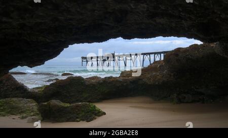 vue sur un quai depuis l'intérieur d'une grotte sur une plage Banque D'Images