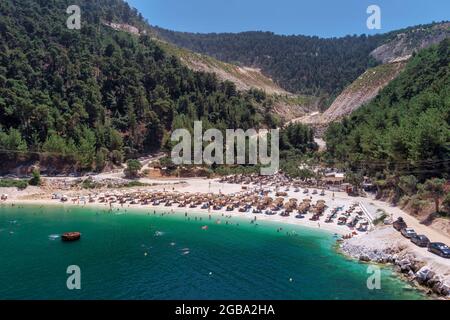 Vue de dessus, vue aérienne d'une émeraude et transparente mer Méditerranée avec une plage blanche pleine de parasols et des touristes qui se détendre et de swi Banque D'Images