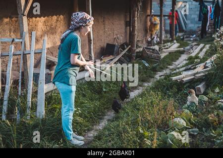 Jolie fille nourrissant des poulets dans le village Banque D'Images