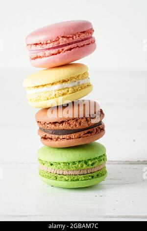 Quatre macarons colorés sur fond rustique en bois blanc. Macarons de petits gâteaux français doux et colorés. Banque D'Images