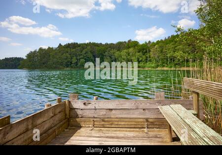 Banc sur une plate-forme de pêche en bois au bord d'un lac par une journée ensoleillée, en Pologne. Banque D'Images