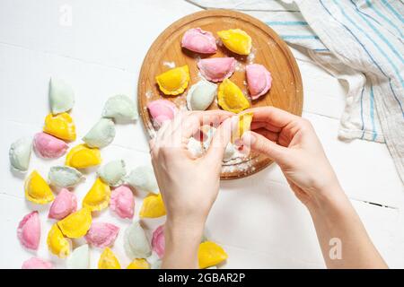 les femmes font des boulettes colorées avec de la viande sur fond de bois blanc. vue de dessus Banque D'Images