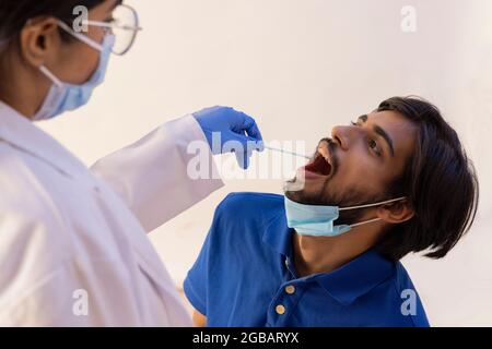 Une femme médecin effectuant le test d'écouvillonnage pour la corona sur un jeune homme. Banque D'Images