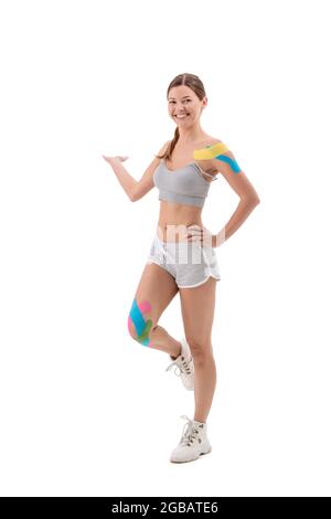 Femme montrant des cassettes kinesio sur son corps. Portrait complet de la femme avec des cassettes kinésio médicales lumineuses Banque D'Images