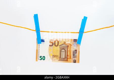 billets en euros attachés avec des épingles à linge à une corde sur fond blanc isolé Banque D'Images