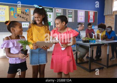 Trois jeunes filles afro-américaines souriantes se regardant l'une l'autre dans la classe de l'environnement à l'école Banque D'Images