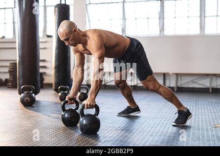 Homme caucasien faisant de l'exercice à la salle de gym, faisant des push-up en utilisant des poids Banque D'Images