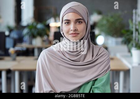 Jeune femme musulmane heureuse dans le hijab debout dans un environnement de bureau Banque D'Images