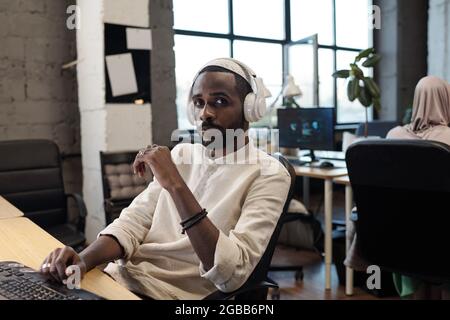 Un jeune homme d'affaires africain sérieux qui regarde la caméra contre son collègue au bureau Banque D'Images