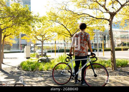 Homme afro-américain en ville tenant son vélo Banque D'Images