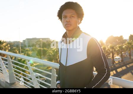 Portrait d'un homme afro-américain en forme s'exerçant en ville avec des écouteurs dans la rue Banque D'Images