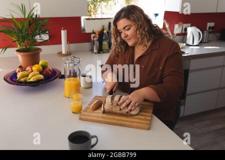 Femme caucasienne préparant le petit déjeuner et buvant du café dans la cuisine Banque D'Images