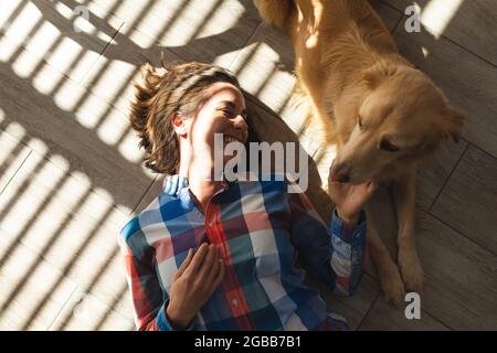 Femme caucasienne couchée sur le sol souriant et petant son chien Banque D'Images