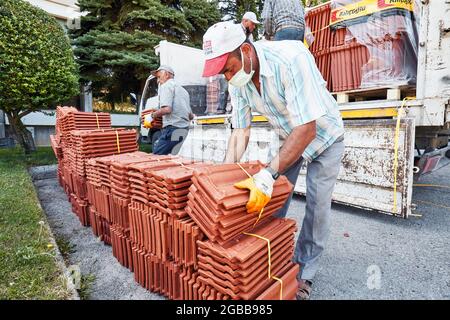 Ankara, Turquie - juillet 2021: Les ouvriers de la construction portant des masques protecteurs déchargent un camion plein de tuiles de toit. Banque D'Images