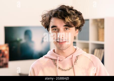 Adolescent contemporain à capuche rose regardant l'appareil photo dans un environnement domestique Banque D'Images