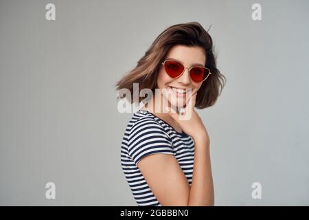 femme blonde portant des lunettes de soleil tient la main près du visage court vue studio Banque D'Images