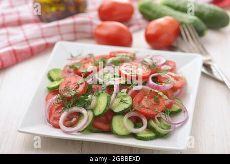 Salade végétarienne de légumes frais avec concombre, tomate et oignon rouge sur une table en bois blanc Banque D'Images