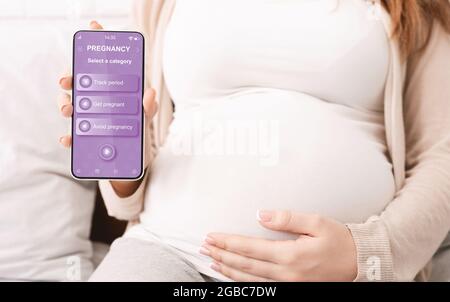 Femme enceinte montrant une application mobile pour la grossesse Banque D'Images