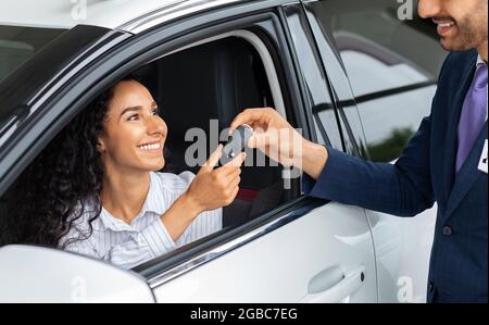 Bonne femme d'affaires qui achète une nouvelle voiture de luxe dans la salle d'exposition Banque D'Images