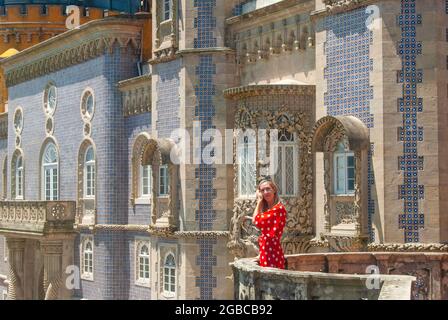 Femme en robe rouge pose devant le bluewall conçu dans un style moderniste partie du Palais Pena Banque D'Images