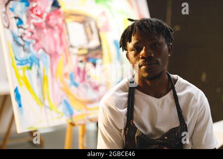 Portrait d'un peintre afro-américain au travail regardant un appareil photo dans un studio d'art Banque D'Images