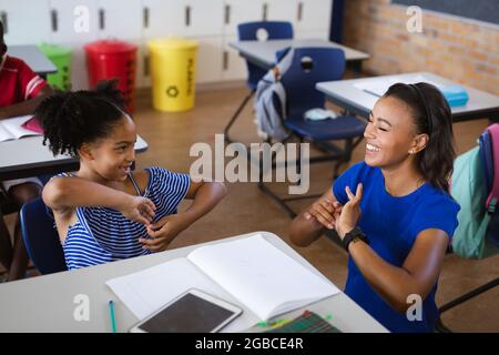 Une enseignante afro-américaine et une fille parlant à la main en langue des signes à l'école élémentaire Banque D'Images