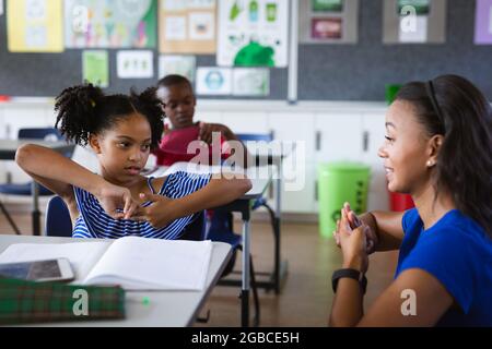 Une enseignante afro-américaine et une fille parlant à la main en langue des signes à l'école élémentaire Banque D'Images