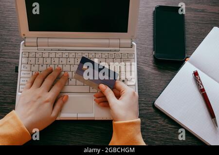 Femme faisant des achats en ligne sur Internet à l'aide d'un ordinateur portable. Les mains sont en possession d'une carte de crédit. Concept de remise et de vente. Banque D'Images