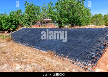 Large gamme de tuyaux noirs utilisés comme système solaire de chauffage de l'eau pour une piscine. Solution écologique et renouvelable d'énergie située dans un jardin Banque D'Images