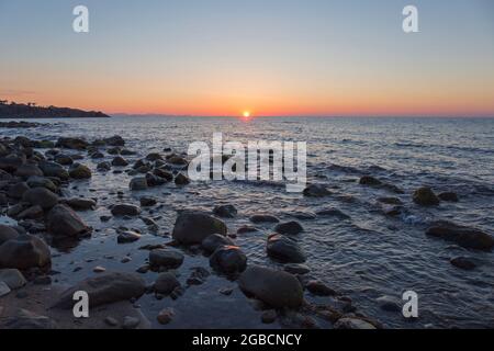 Cefalù, Palerme, Sicile, Italie. Vue sur les eaux tranquilles de la mer Tyrrhénienne depuis le rivage rocheux, coucher de soleil. Banque D'Images