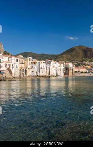 Cefalù, Palerme, Sicile, Italie. Vue sur le port tranquille jusqu'à la vieille ville, maisons suspendues regroupées le long du front de mer.