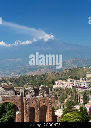 Taormina, Messine, Sicile, Italie. Vue sur le sommet couvert de nuages de l'Etna depuis le théâtre grec, arches ruinées en premier plan. Banque D'Images