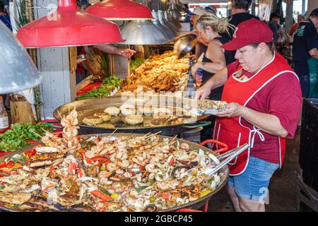 Everglades City Florida, Seafood Festival food, stand fournisseur crevettes crevettes crevettes paella crabe gâteaux, femme hispanique cuisinière femme cuisine préparation assiette dis Banque D'Images