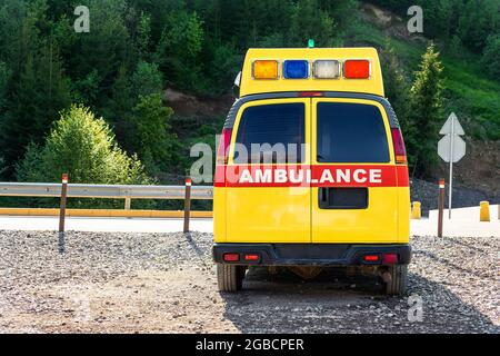 Vue de la porte arrière de l'ambulance jaune secours ems voiture garée près de campagne route rurale dans la région de la montagne de montagne de haute. Aide de premiers soins paramédic Banque D'Images