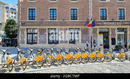 Une rangée de vélos à louer garés sur la place centrale en face de l'hôtel Novotel par beau temps. Banque D'Images