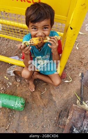 New Delhi, Inde. 17 juin 2017. Un garçon indien qui mange du maïs. Banque D'Images