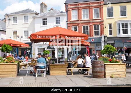 Visiteurs personnes assises sous les parasols de Brecon de bienvenue aux tables de pique-nique à l'extérieur de l'église St Marys dans le centre-ville été 2021 Powys Wales UK KATHY DEWITT Banque D'Images