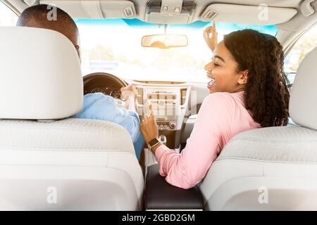 Heureux couple noir appréciant la musique au volant de voiture Banque D'Images